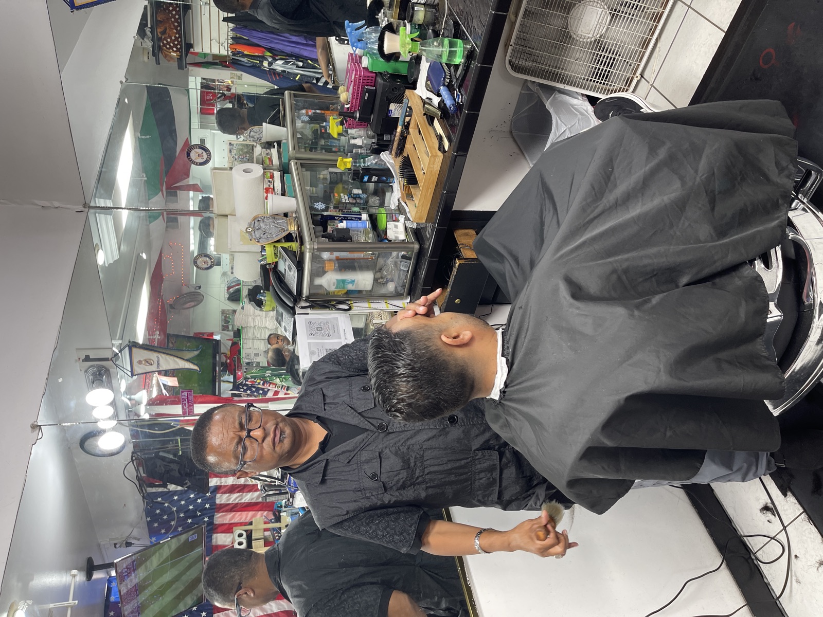 A barber working on a customer's cut at his station