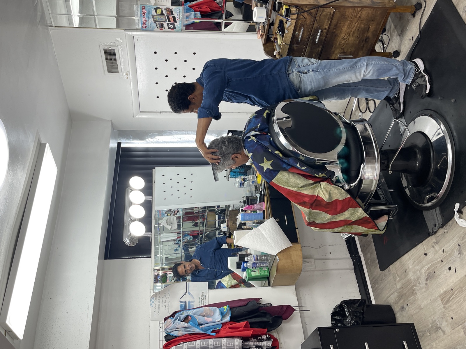 A barber cutting hair in the shop's bright second room